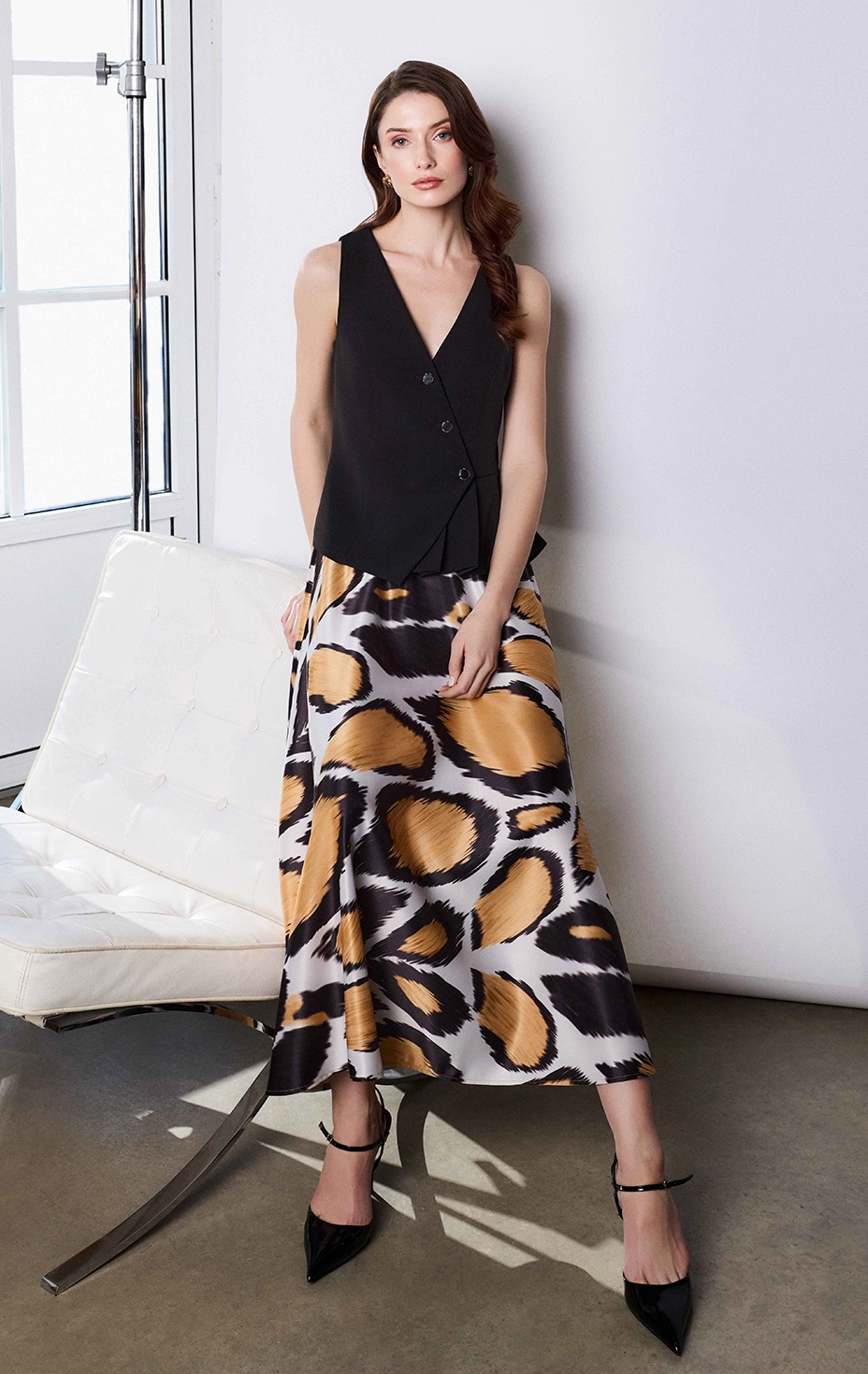 Fustă din satin cu imprimeu stilizat în galben și negru, combinată cu o vestă asimetrică neagră cu nasturi.