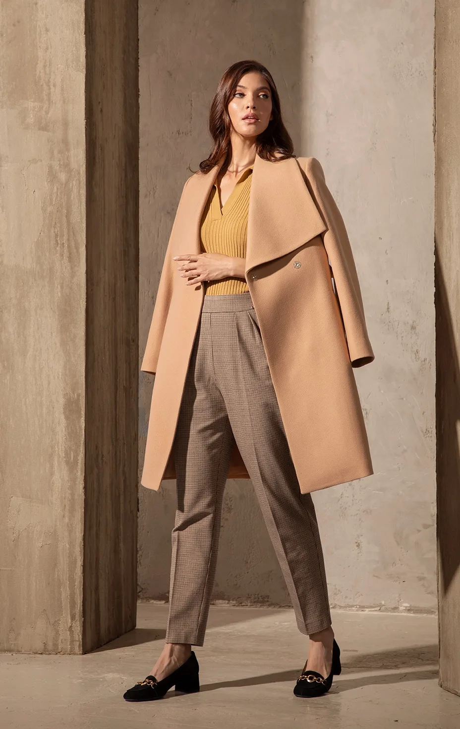 Elegant women’s look with beige coat, knitted top and checked trousers